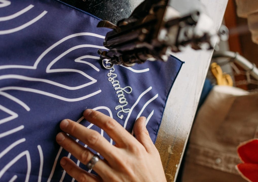 Person sowing designs into a bandana